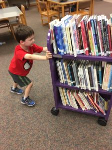 boy moving books on book cart