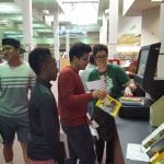 students getting help checking out books at the self check-out station